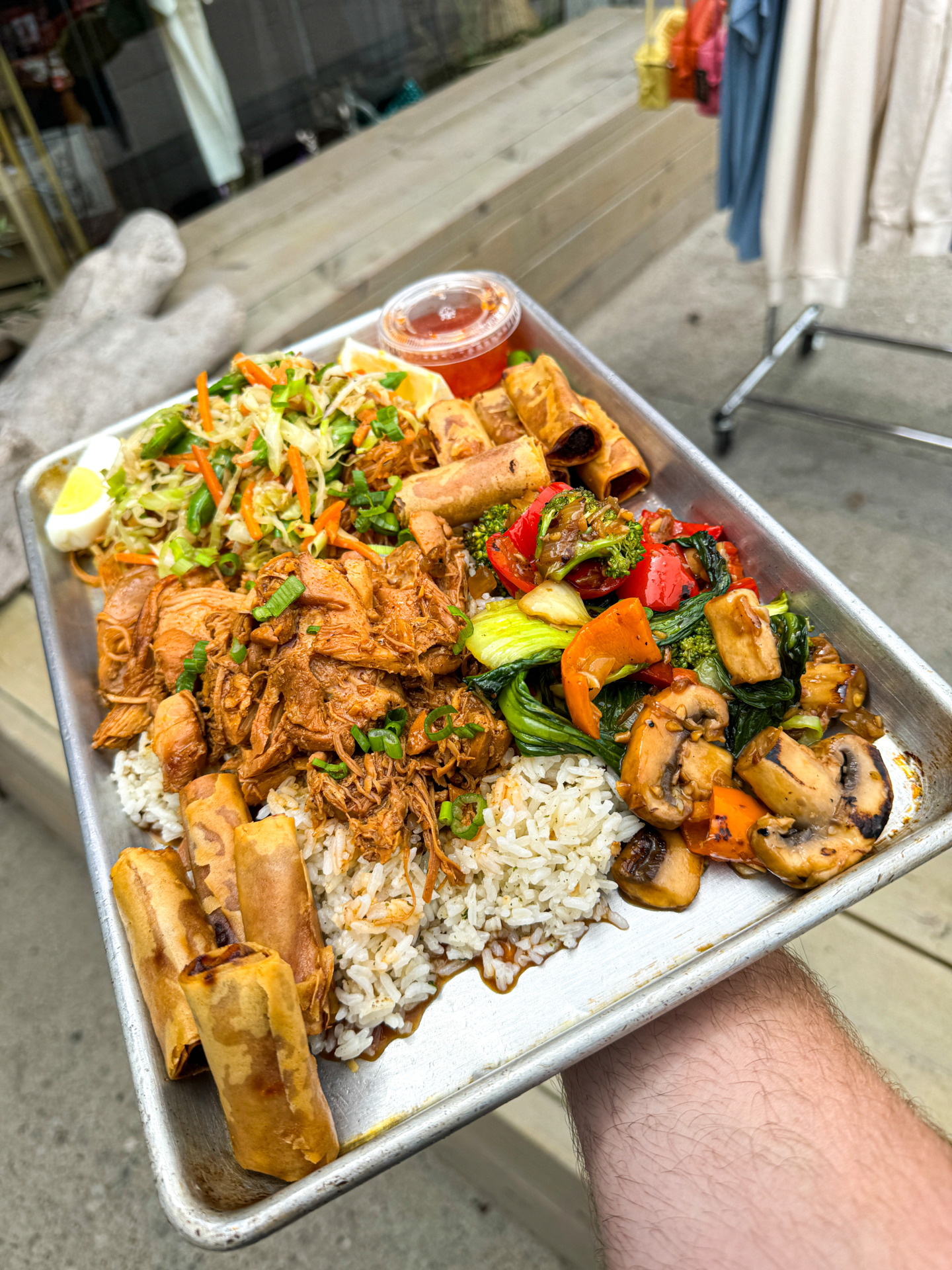 A loaded tray of dishes like Pancit Noodles, Lumpia, Garlic Rice, and Chicken Adobo from Big Boi in Los Angeles